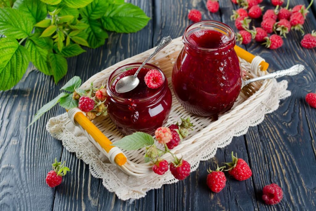 borcane cu dulceata de zmeura in ladita impletita pe masa rustica