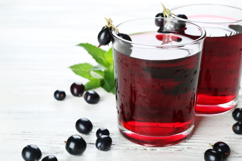 pahare cu sirop natural de coacaze negre pe masa rustica alba