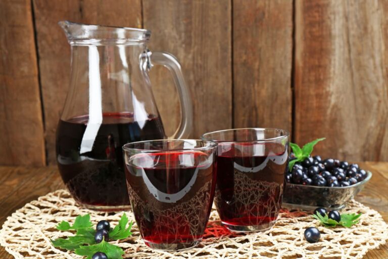 pahare si carafa cu sirop de coacaze negre pe masa rustica cu broderie