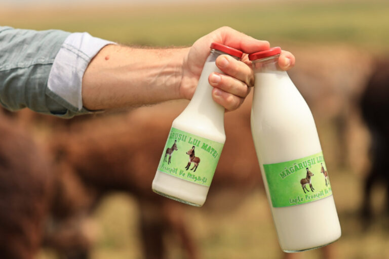 producator locale care tine in mana doua sticle cu lapte de magarita proaspat