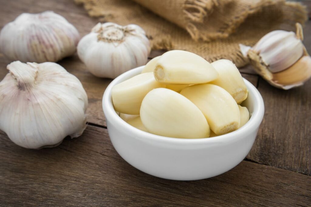 sturoi romanesc si catei de usturoi curatati in bol pe masa rustica